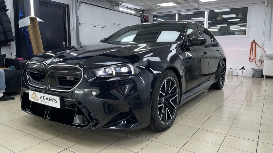 Чёрный BMW в боксе студии, кузов с глубоким глянцем и чёткими бликами