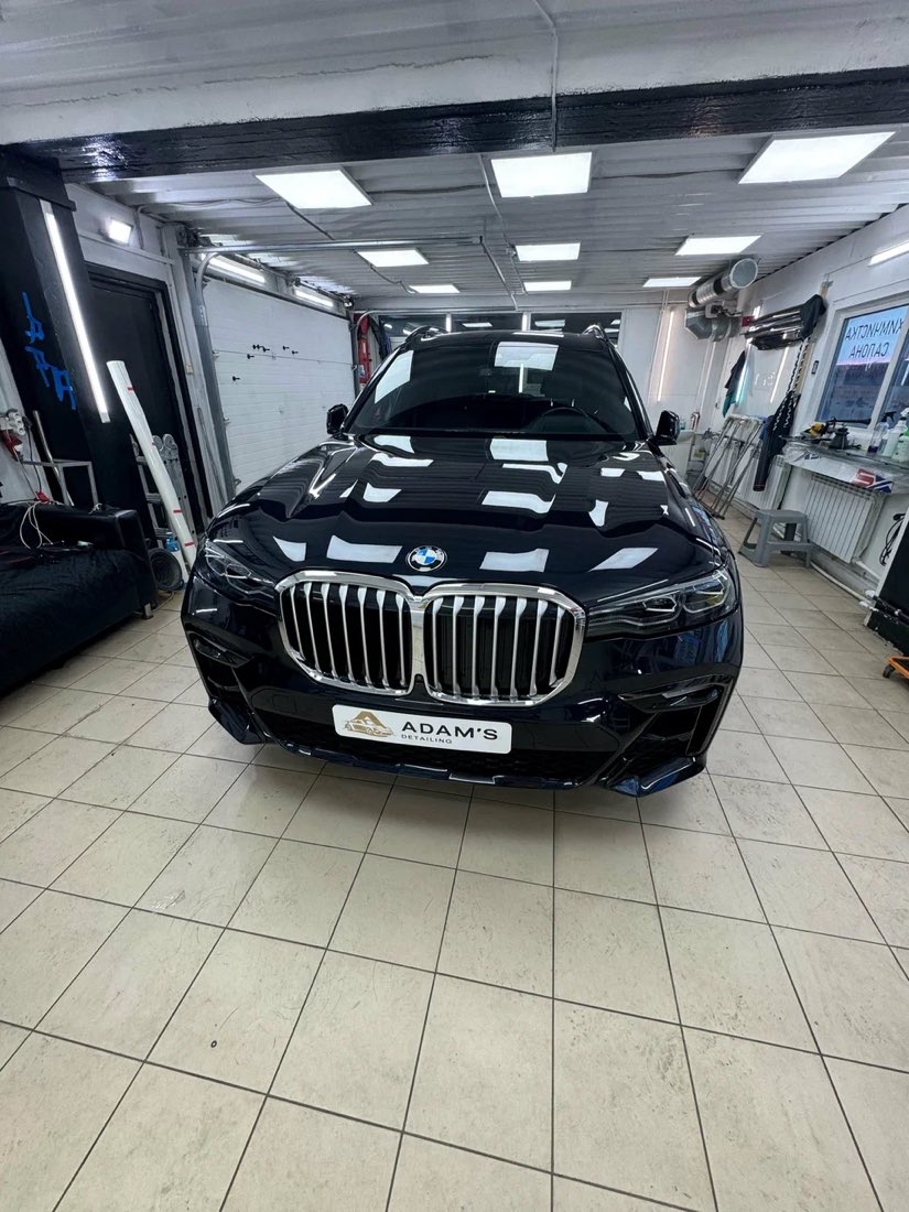 Чёрный BMW X7 в боксе студии, вид спереди, глянцевый кузов