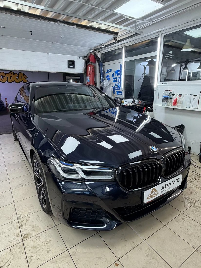 Чёрный седан BMW в боксе студии, вид спереди, глянцевый кузов